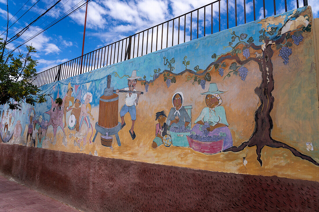 A wall mural depicting people making wine in Cafayate, Argentina.