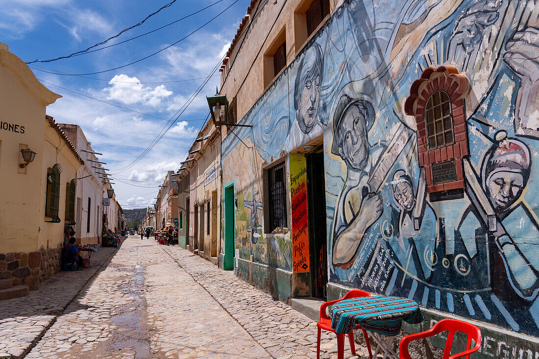 Colorful murals on a cobblestone street in Humahuaca in the Humahuaca Valley or Quebrada de Humahuaca, Argentina.