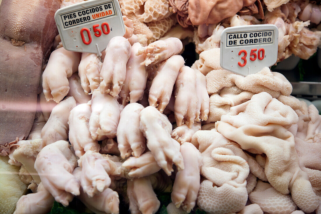 A variety of lamb trotters and tripe displayed for sale at a butcher shop in La Boqueria, showcasing local culinary offerings.