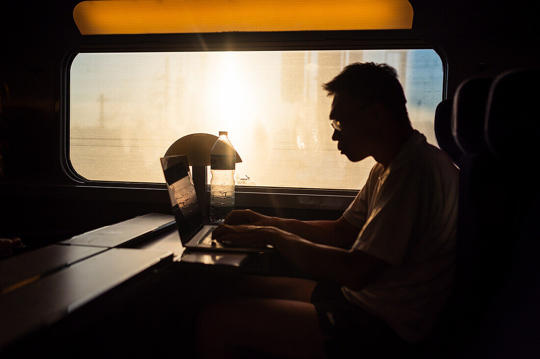 Silhouette of man working with his laptop in the high speed AVE train, Spain