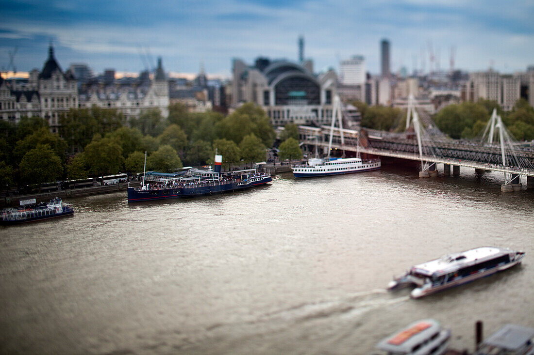 A busy Thames River teems with boats, with Hungerford Bridge gracefully arching in the background, showcasing Londons vibrancy.