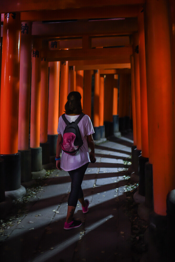 Junge kaukasische Frau erkundet den Fushimi Inari Taisha-Tempel bei Nacht, Kyoto, Japan