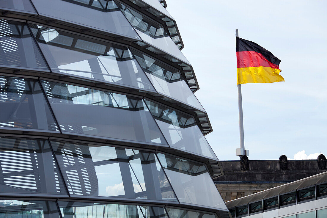 The iconic Reichstag roof dome showcases modern architecture while the German flag proudly waves in the background over Berlin.