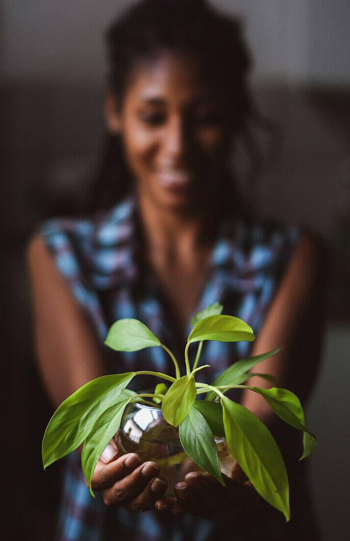 Young afro latin woman gardening and holding an hydroponic plant