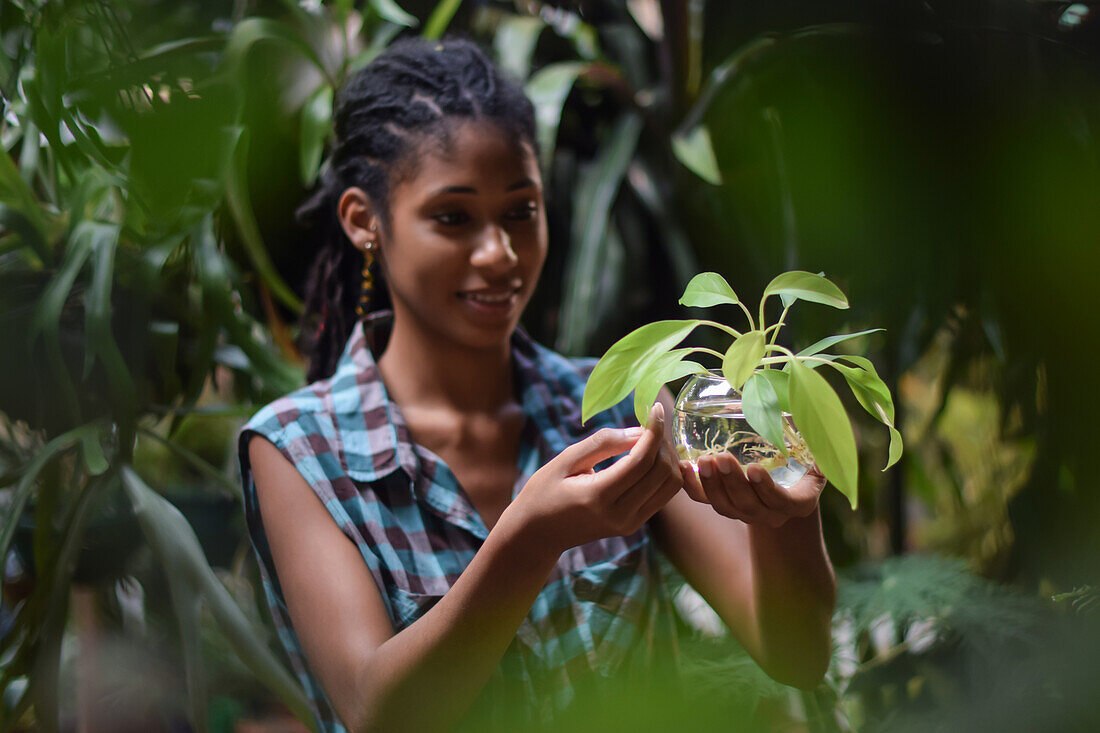 Young afro latin woman gardening and holding an hydroponic plant