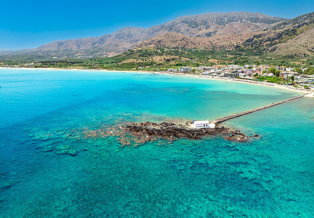 Drohnenaufnahme von Georgioupoli und der berühmten Kapelle von Agios Nikolaos, die auf dem Meer gebaut wurde, mit einem kleinen Weg, der zum Festland führt, Chania, Kreta, Griechische Inseln, Griechenland, Europa