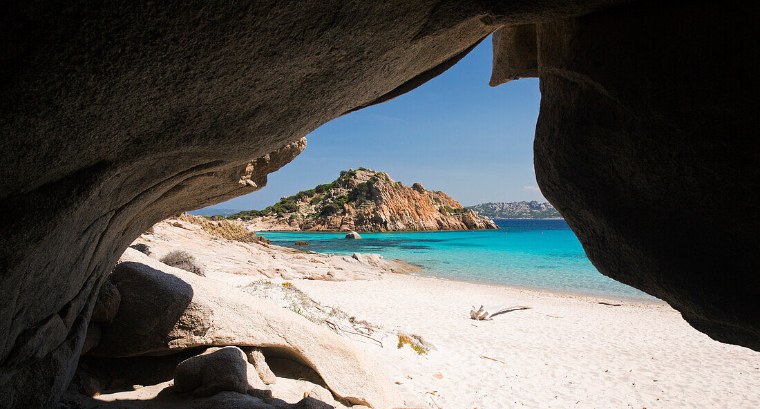 Blick durch den Höhleneingang über das klare türkisfarbene Wasser der Cala Corsara auf die rosafarbene Granitspitze der Punta Rossa Corsara, Insel Spargi, Nationalpark La Maddalena Archipelago, Sassari, Sardinien, Italien, Mittelmeer, Europa