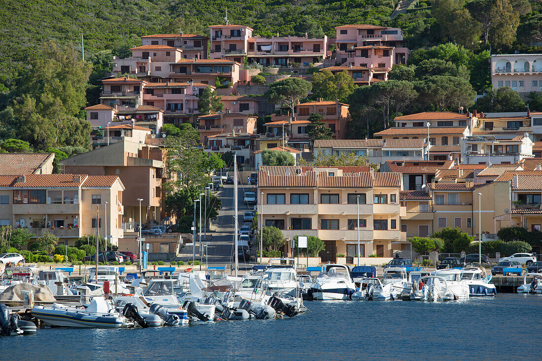 Blick über den Yachthafen auf die Uferpromenade, moderne Häuser klammern sich an den bewaldeten Hang dahinter, Palau, Sassari, Sardinien, Italien, Mittelmeer, Europa