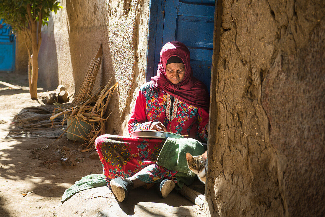 Woman sitting on her doorstep peeling garlic, village of Ramadi, west bank of the Nile south of Edfu, Egypt, North Africa, Africa