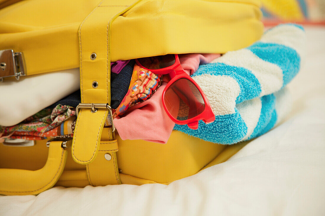 Yellow Suitcase Bursting with Clothing