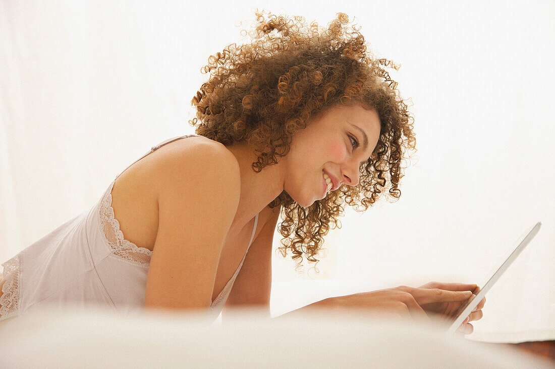 Woman Lying on Bed Using Digital Tablet