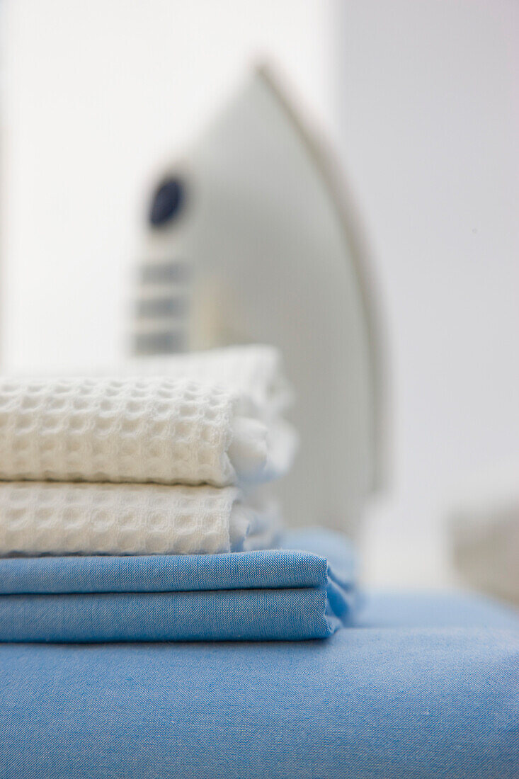 Close up of a stack of bed linen and an iron