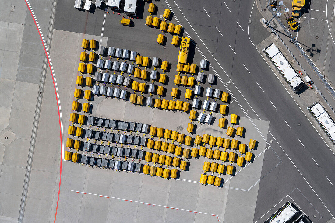 View from above empty yellow and black luggage carts on sunny airport tarmac