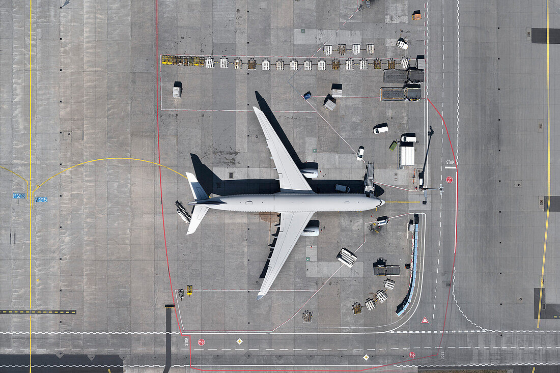 View from above airplane and service vehicles on sunny airport tarmac