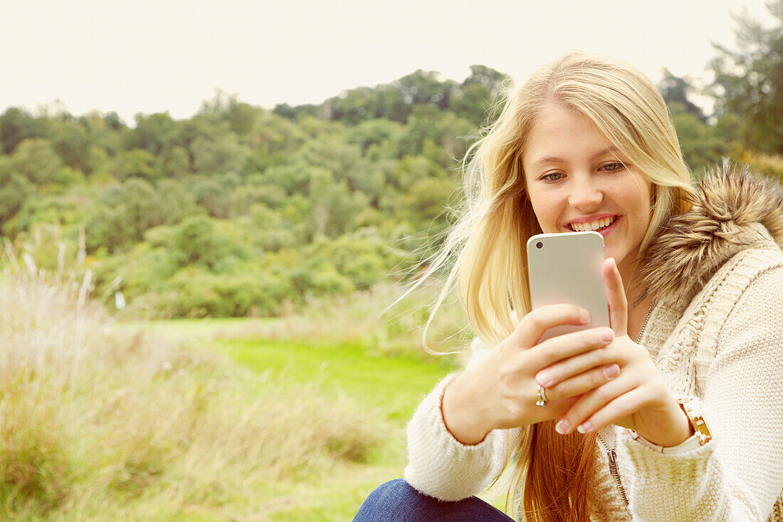 Young Woman in Field Using Smartphone