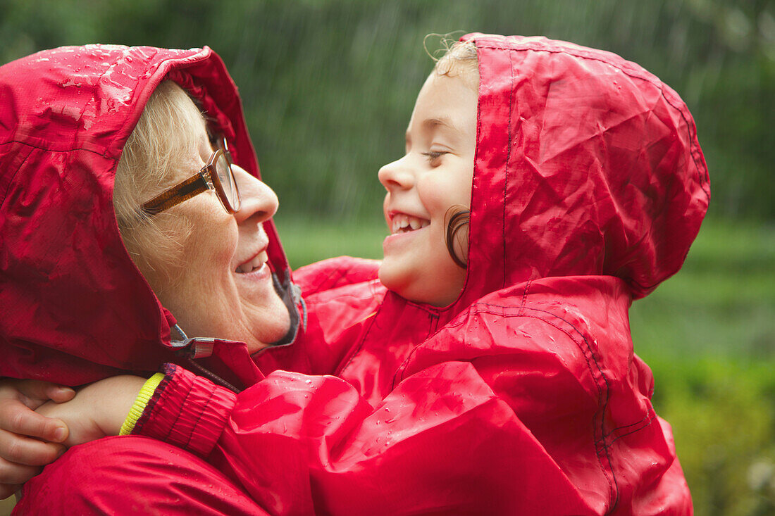 Großmutter und Enkelin umarmen sich im Regen