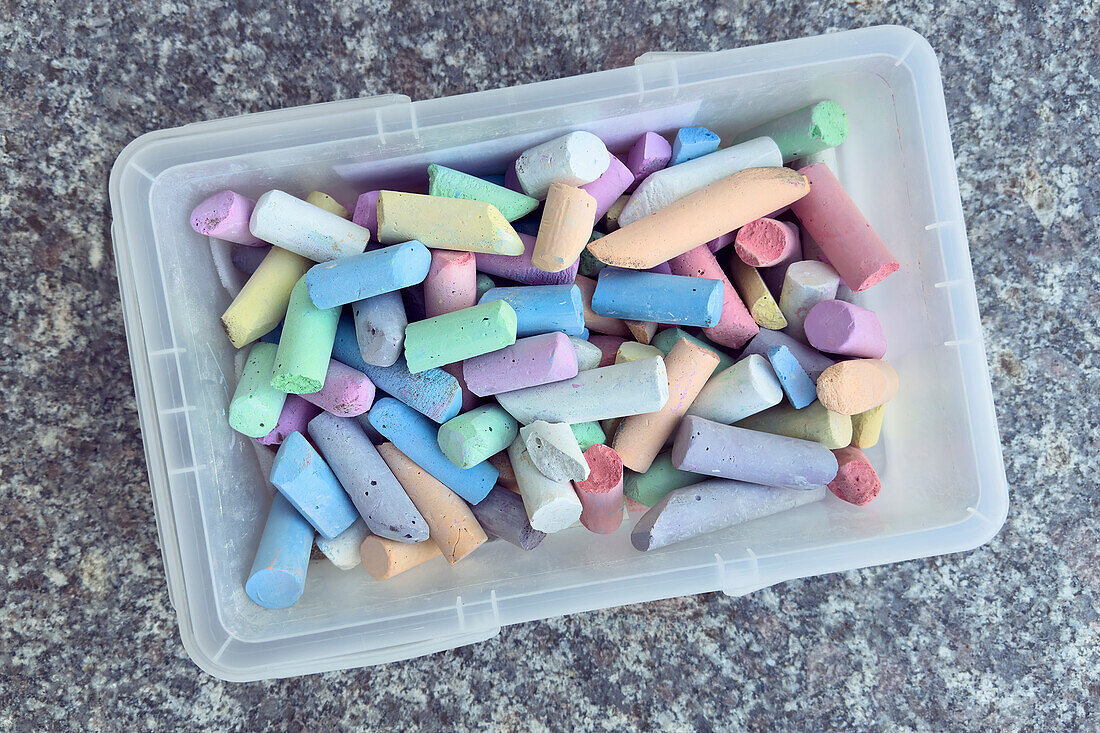 View from above multicolored sidewalk chalk in plastic bin