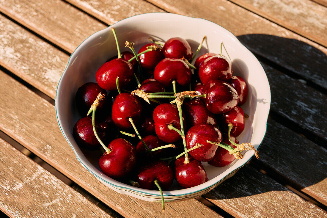 Still life close up vibrant red cherries in bowl on sunny table