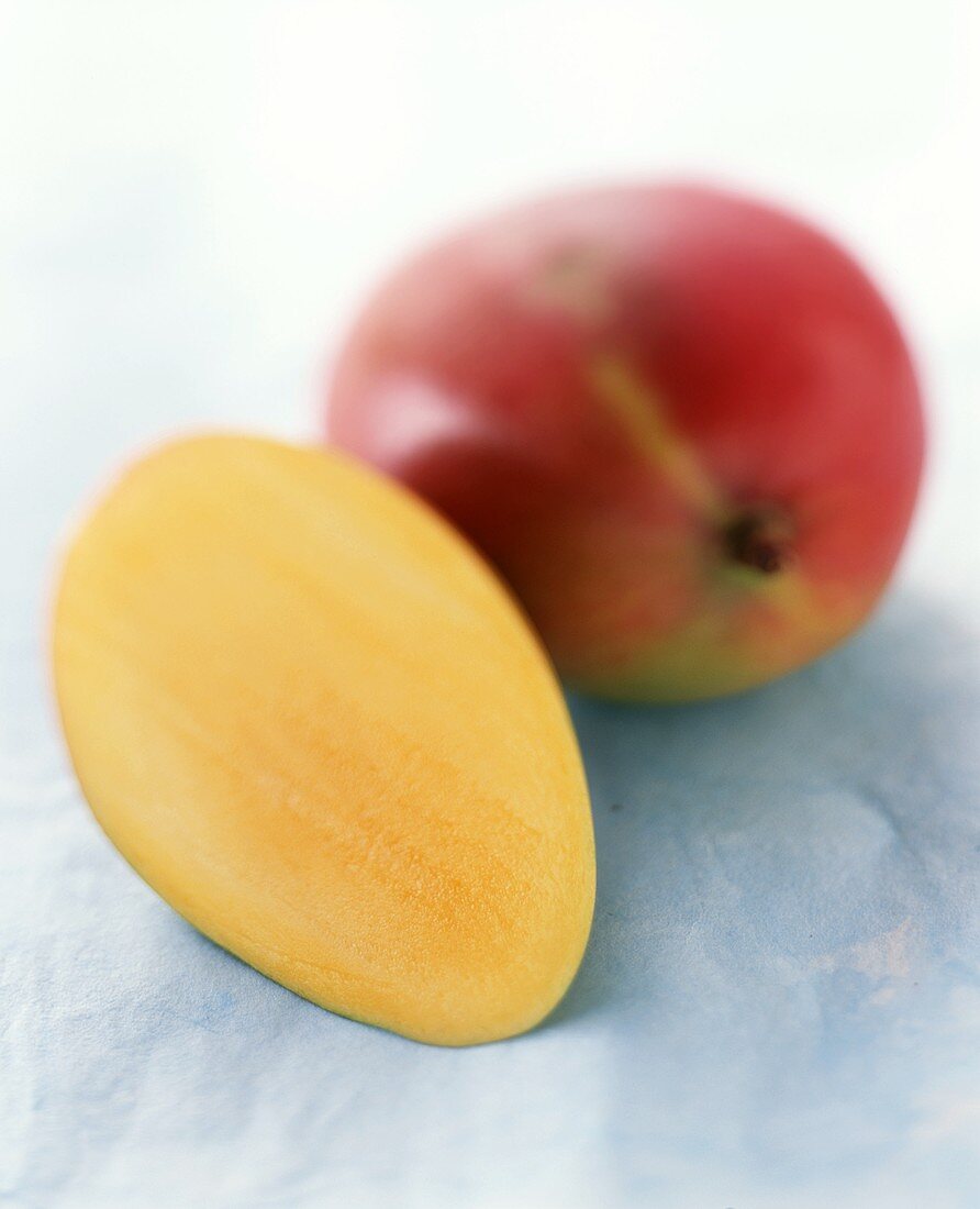 Half a mango beside a whole mango