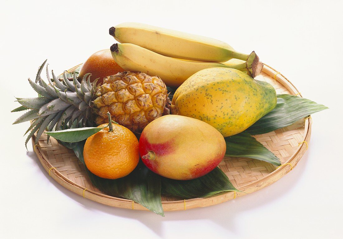Various exotic fruits with mandarin on wicker plate