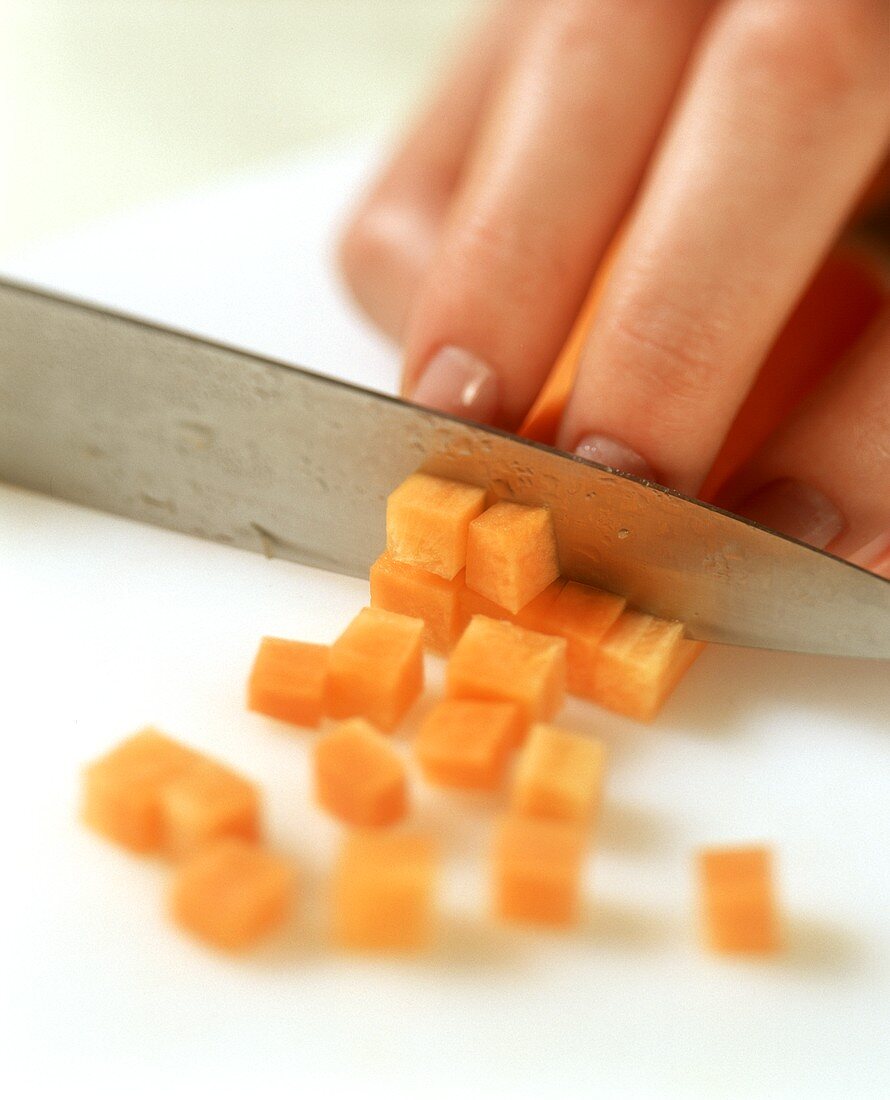Eine Karotte wird in Würfel geschnitten