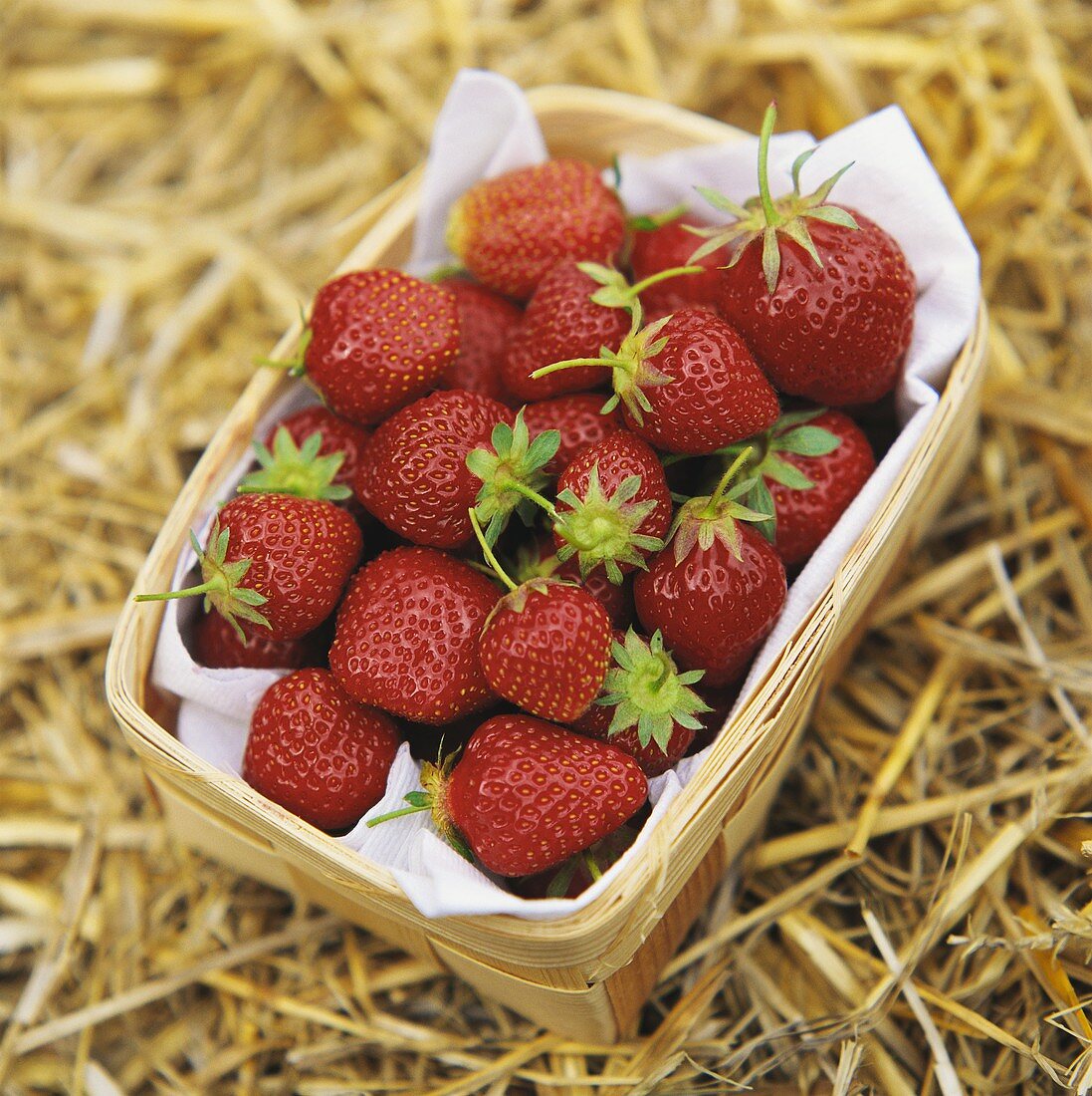 Erdbeeren in Spankörbchen auf Stroh