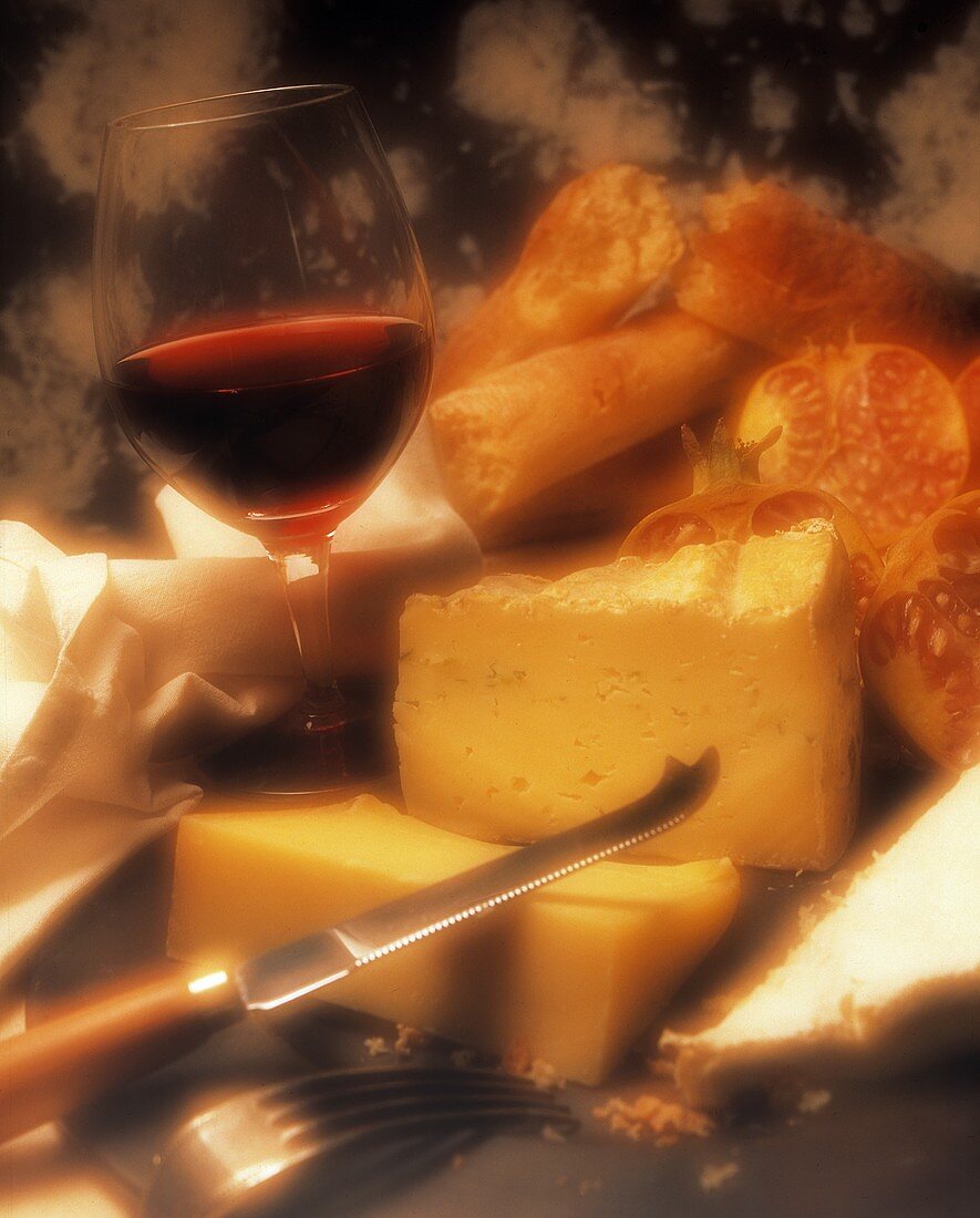 Mehrere Käse, Brot und ein Glas Rotwein