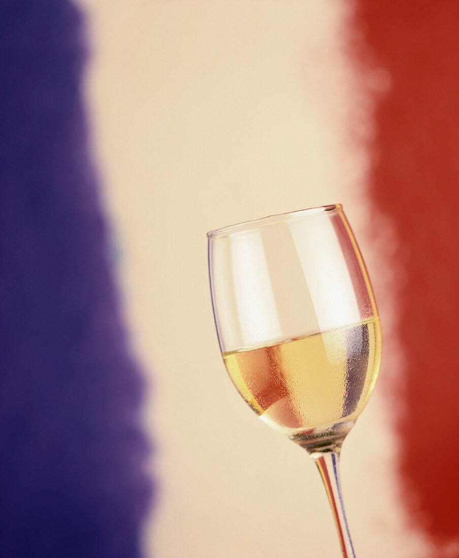 Ein Glas Weißwein vor den französischen Nationalfarben
