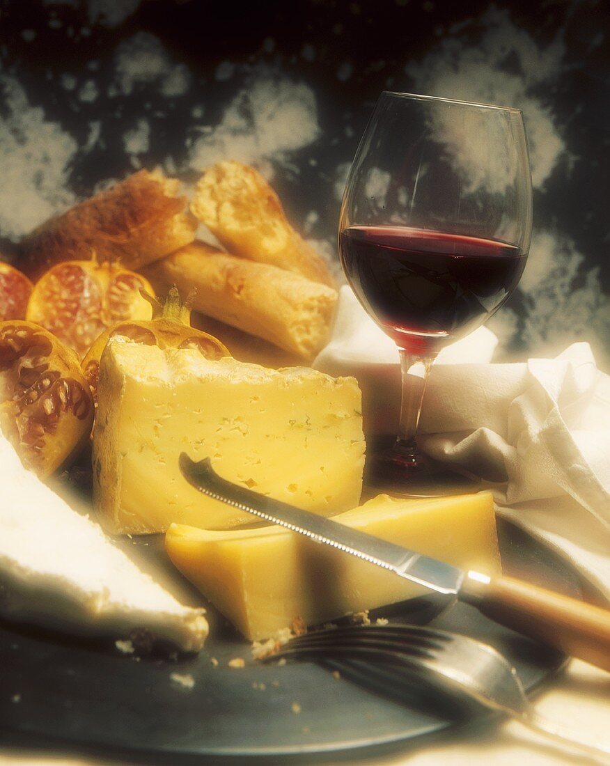 Verschiedene Käsesorten, Brot und Glas Rotwein