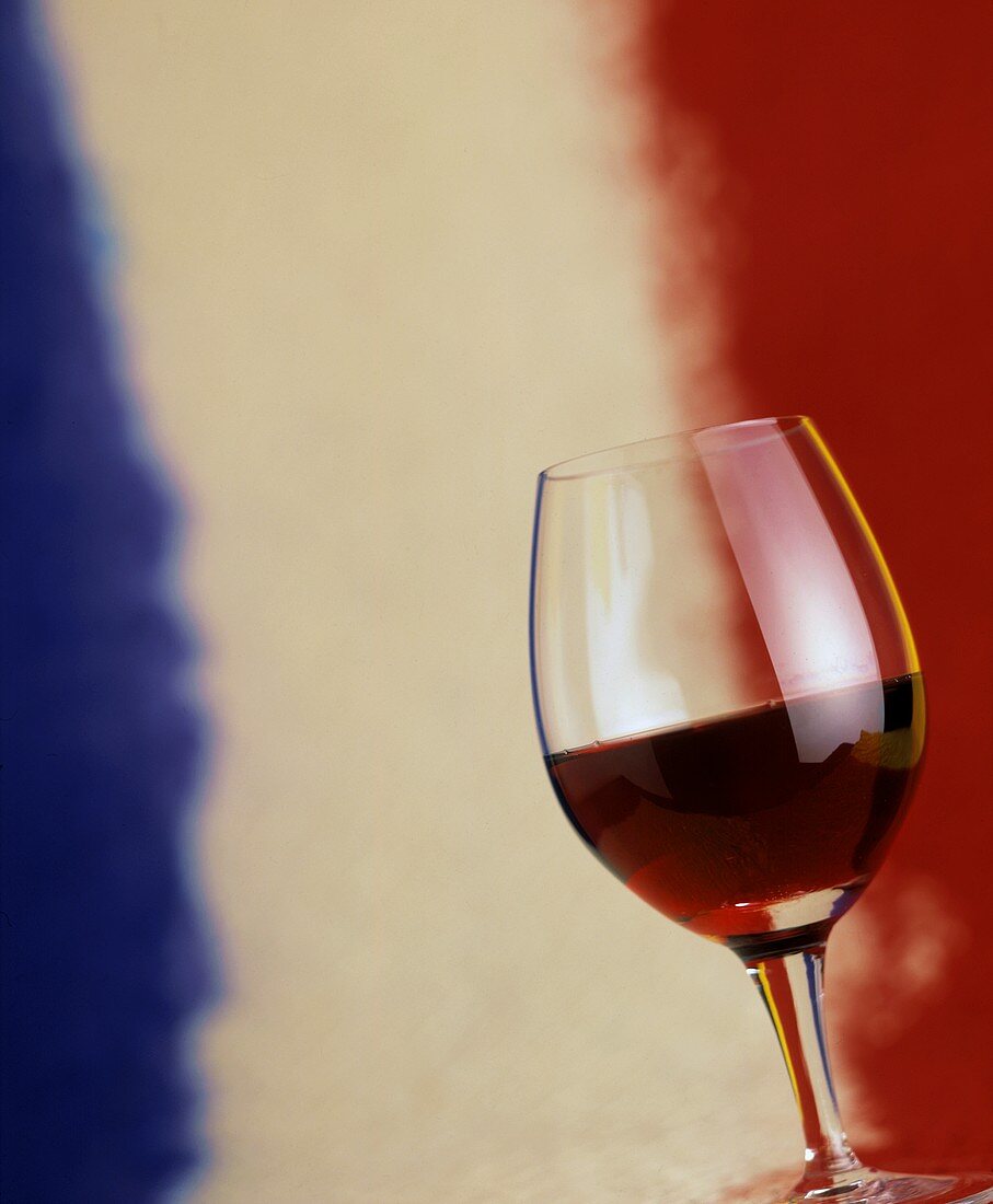 Ein Glas Rotwein vor den französischen Nationalfarben