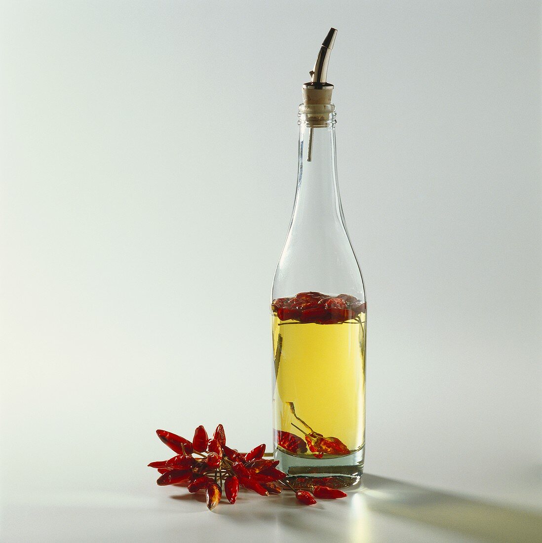 A bottle of chili oil, dried red chilies beside it
