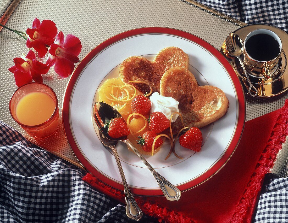 Herzförmige Pancakes mit Erdbeeren, Orangen und Sahne