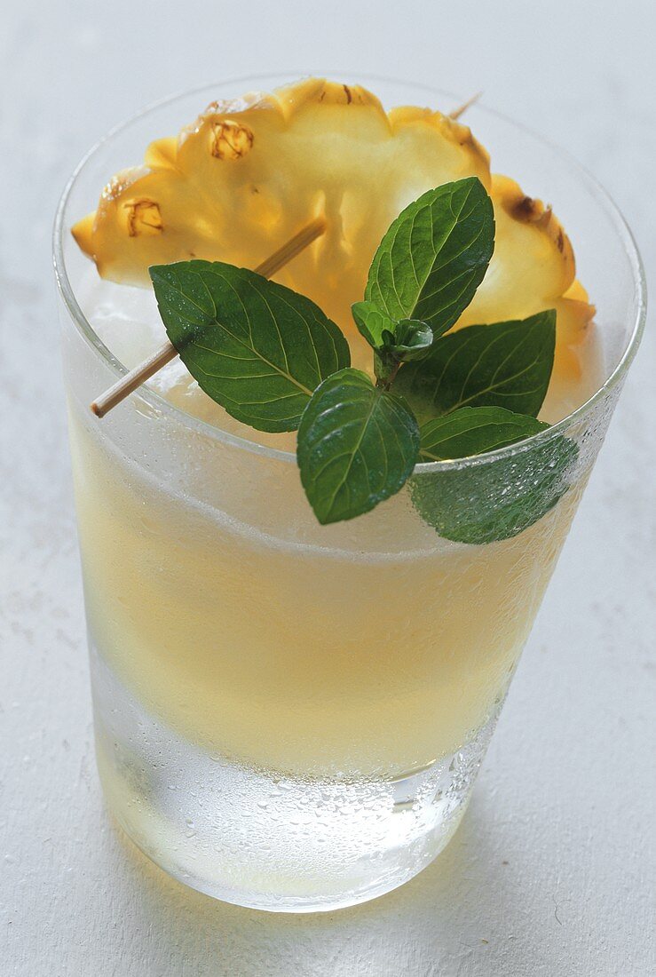 Ananas-Drink im Glas, garniert mit Ananasscheibe und Minze
