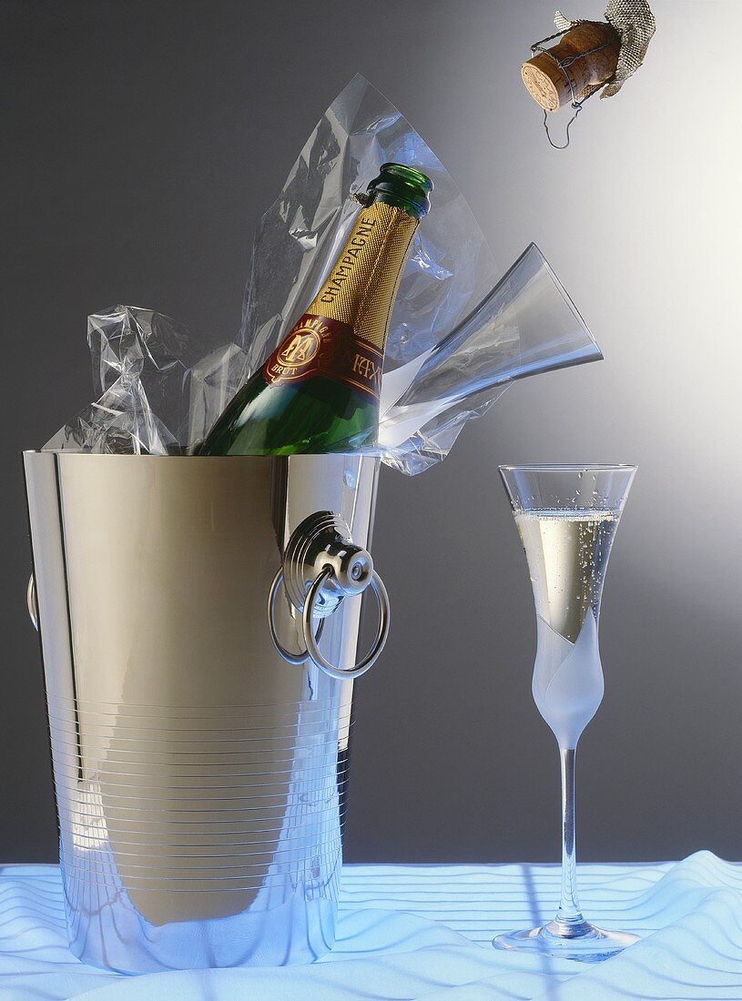 Champagner im Sektkübel und Glas, sowie Champagnerkorken