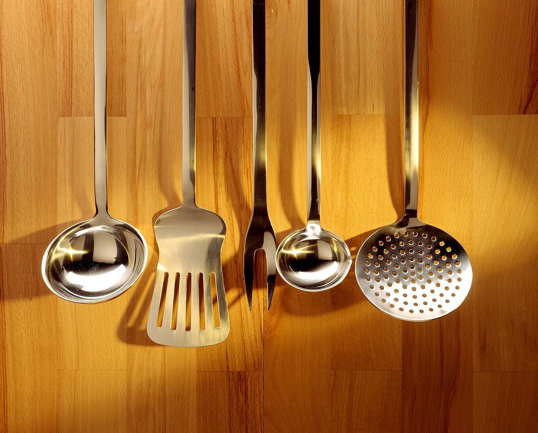 Ladles, spatulas & a meat fork hanging on wooden wall