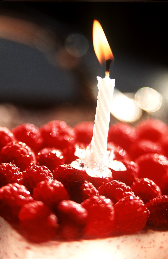 A raspberry slice with a small burning candle