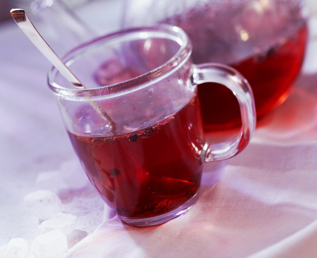 Hot fruit tea (Kaminfeuer) in glass and pot