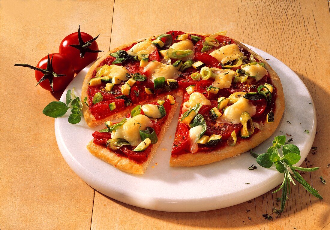 Pizza mit Tomaten, Lauch und Zucchini, angeschnitten