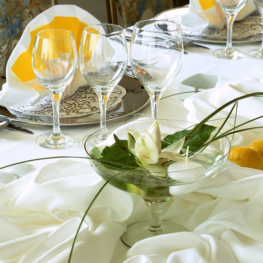 Glass bowl with white flower on laid table (close-up)