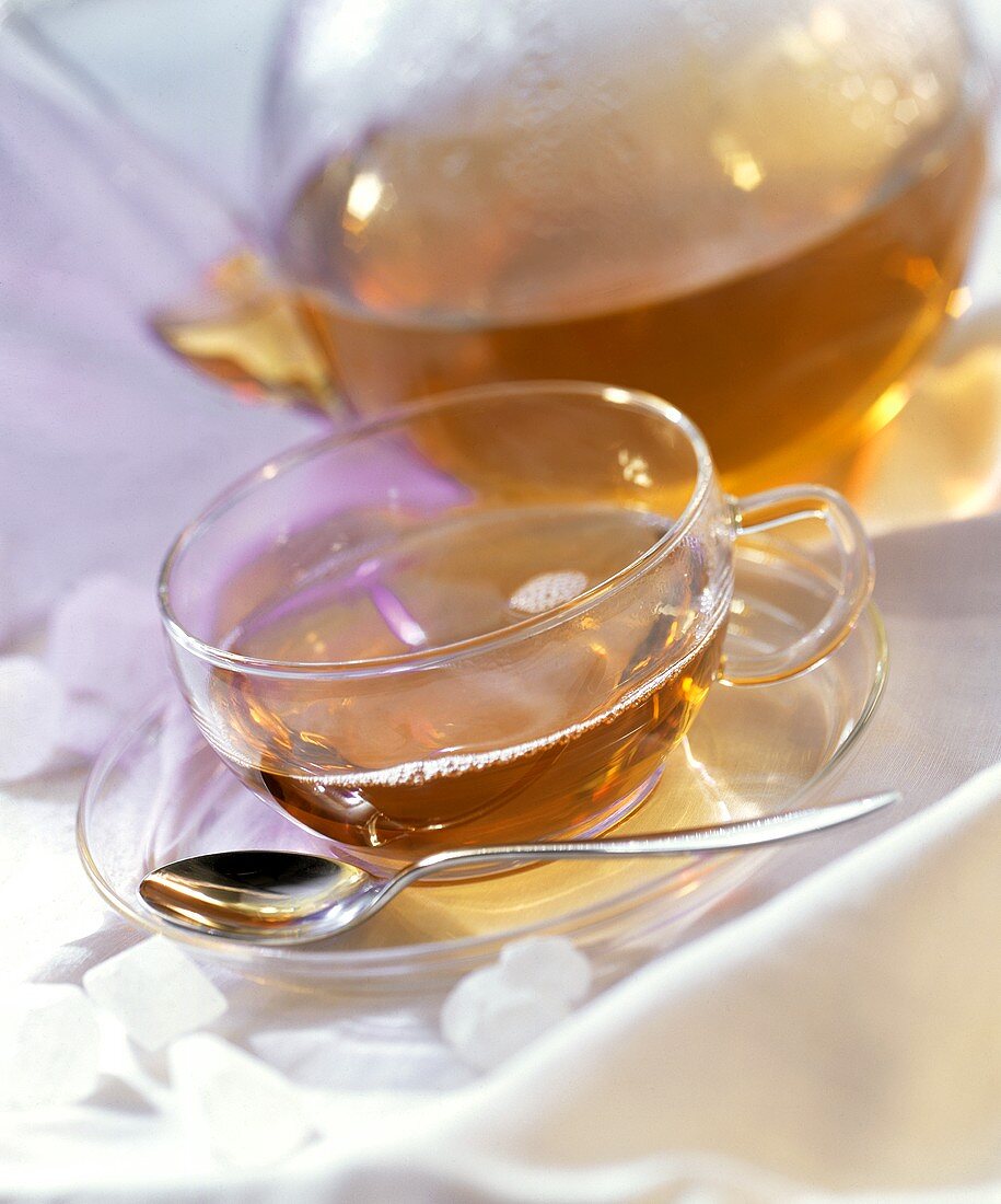 Tee in Glastasse und -kanne; weisser Kandiszucker