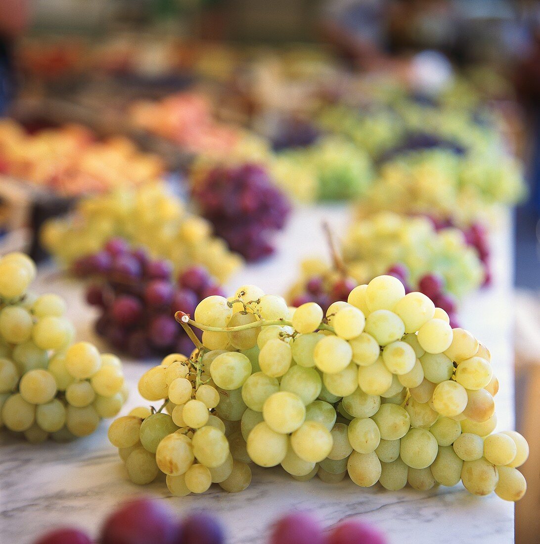 Green and red grapes on marble slab at the market