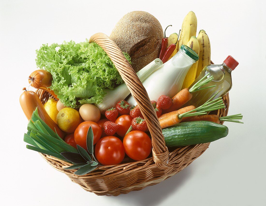 Lebensmittel (Obst, Gemüse, Brot, Milch etc.) im Weidenkorb