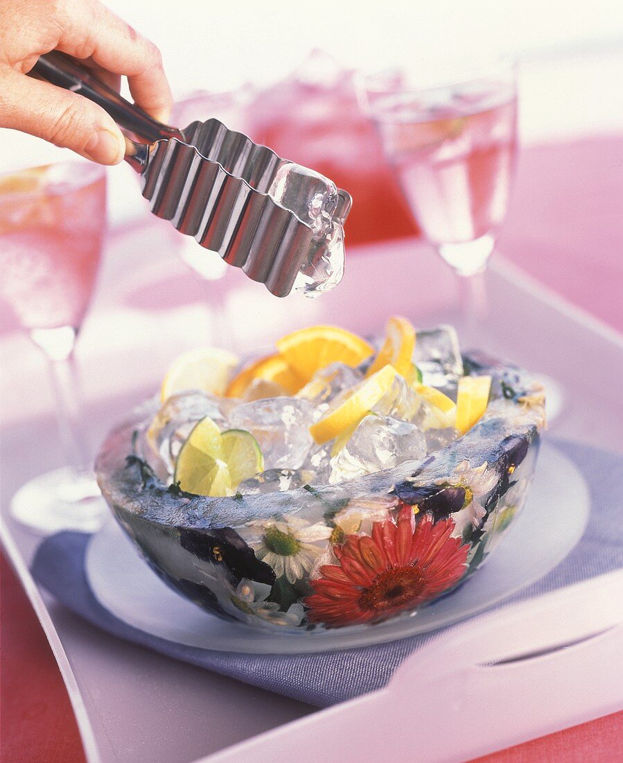 Ice cube in ice bowl with flowers frozen in on table