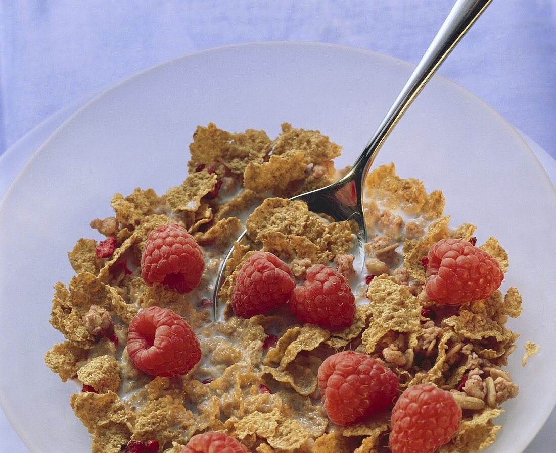 A dish of wholemeal cornflakes, raspberries and milk
