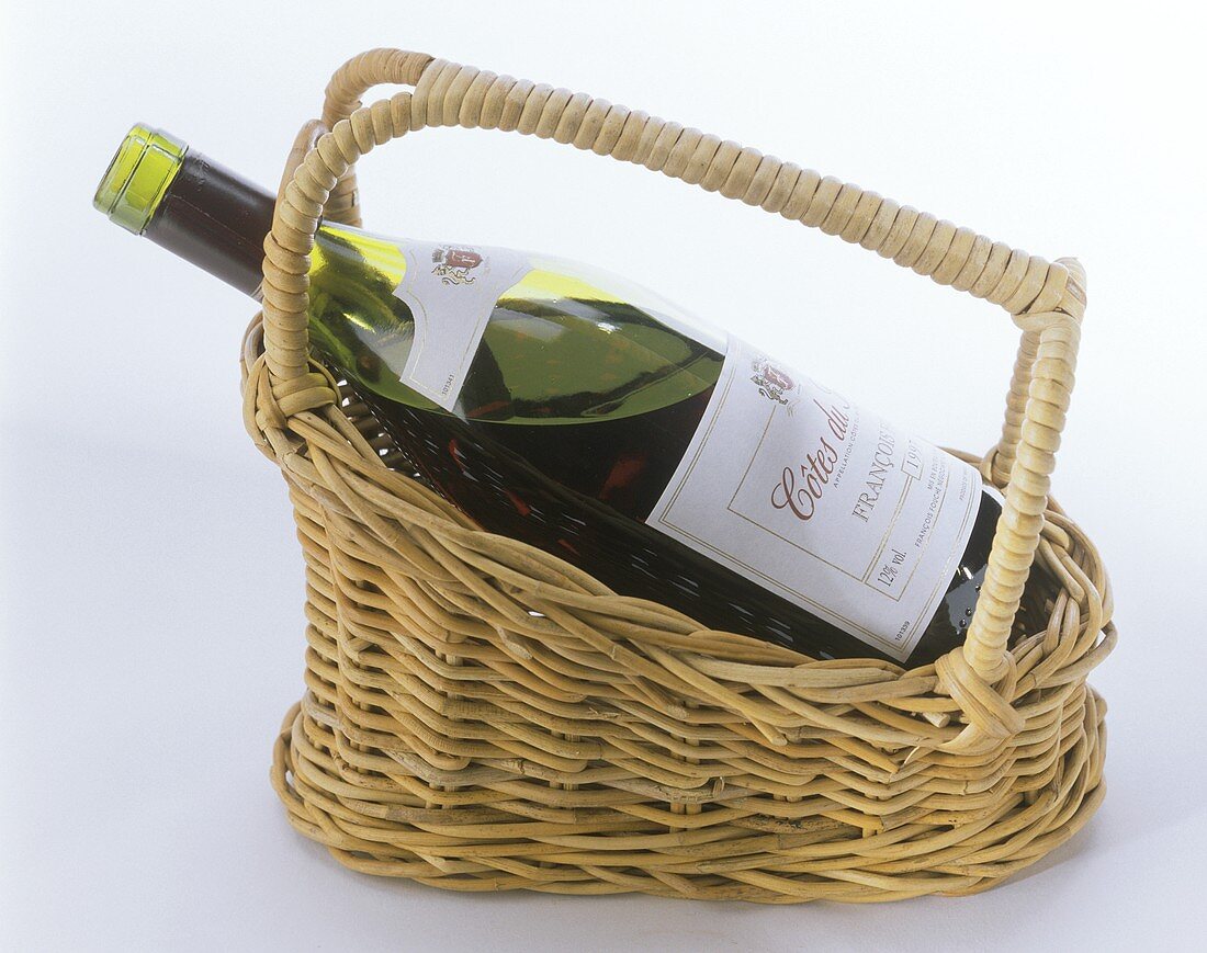 A bottle of red wine in a wine basket