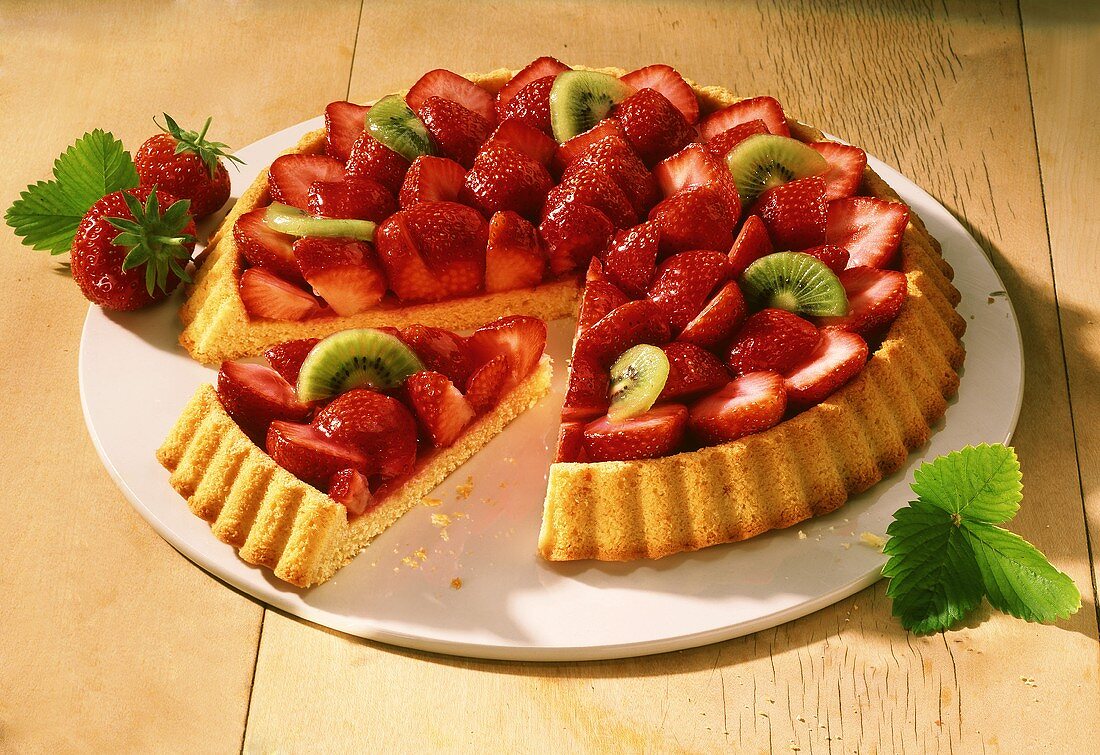 A strawberry flan with kiwi pieces on cake plate
