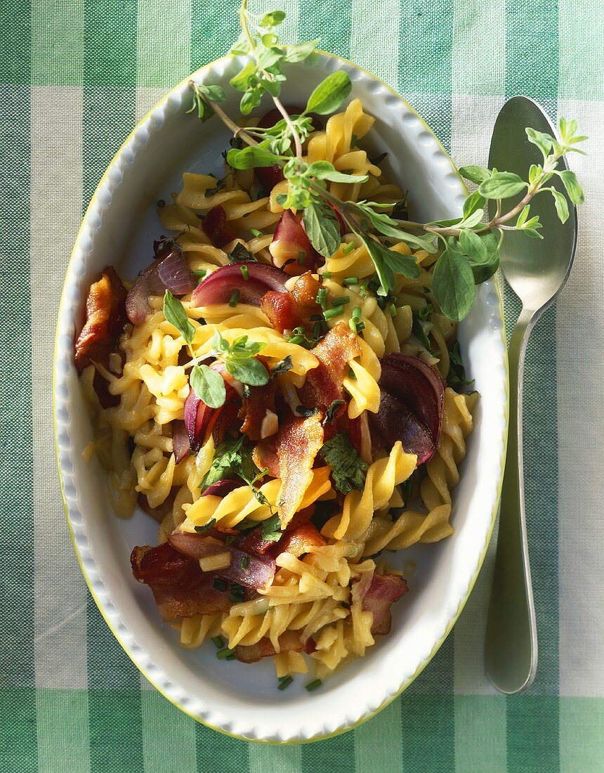 Fusilli with bacon, cheese and red onions in baking dish