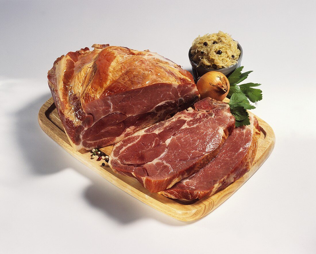 A piece and two slices of raw smoked pork rib; sauerkraut
