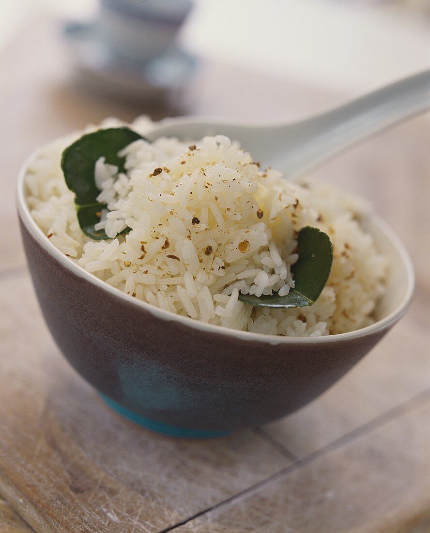 Schälchen Reis mit asiatischen Gewürzen und Zitronenblättern