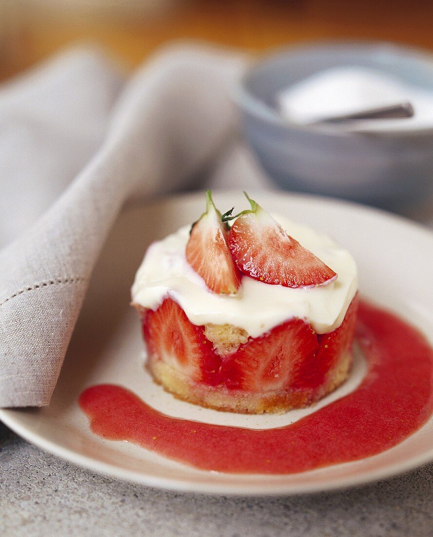Kleines Erdbeertörtchen mit Erdbeersauce auf Teller